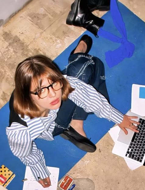 A student sitting on the floor working on a laptop, seen from above